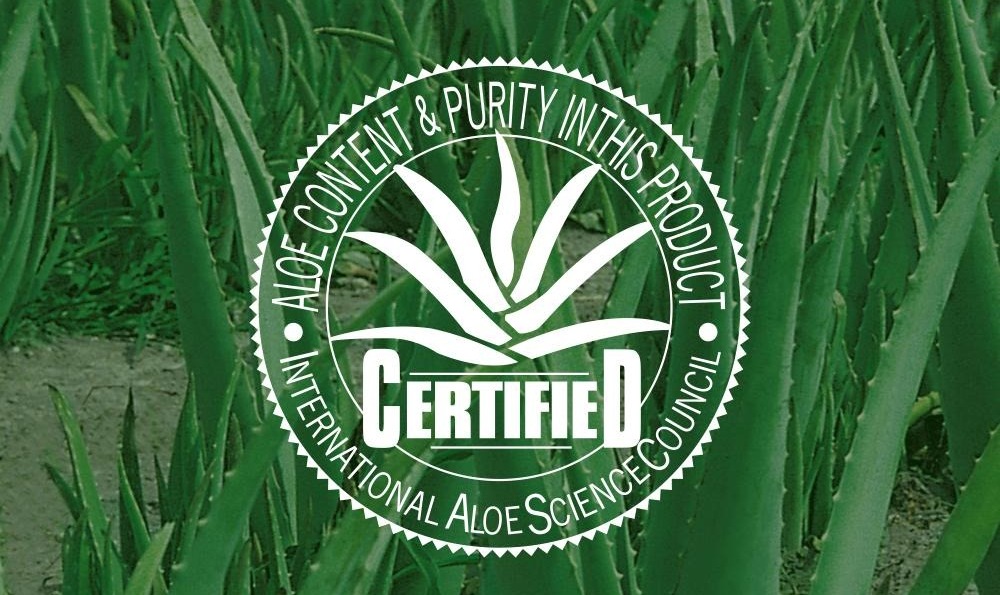 알로에 밭 사진 위에 얹힌 국제알로에기준심의협회 인증 도장. ALOE CONTENT & PURITY IN THIS PRODUCT · CERTIFIED · INTERNATIONAL ALOE SCIENCE COUNCIL