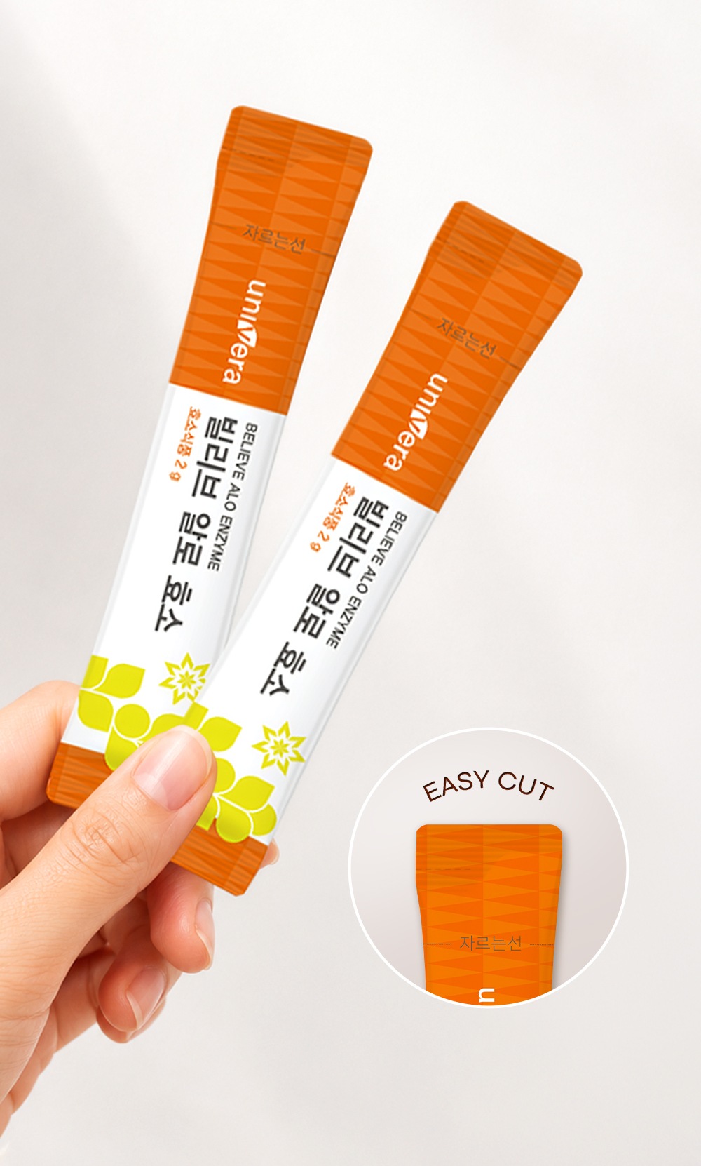 손에 든 빌리브 알로 효소 스틱 두 포와, 스틱 윗부분 자르는선을 확대한 원 — EASY CUT